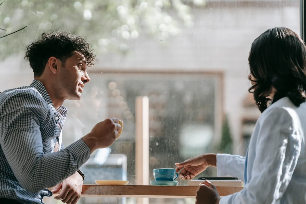 Two people talking over coffee at a café table